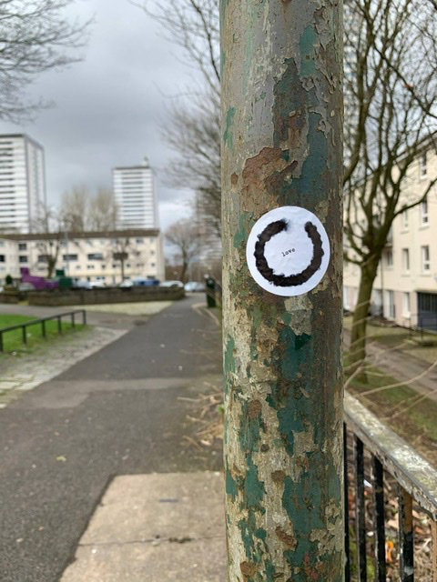 sticker on lamp post in wyndford housing scheme showing an enso by daishin stephenson with the word love at the centre